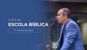 Banner da igreja com fundo azul, contendo o texto “Culto de Escola Bíblica” e, abaixo, “Pr. Wanderley Vilaça”. À direita, há a foto do pastor, vestindo paletó azul, falando em um ambiente interno de igreja.